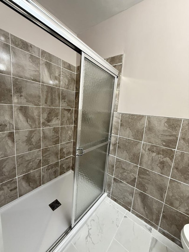 bathroom featuring an enclosed shower and toilet