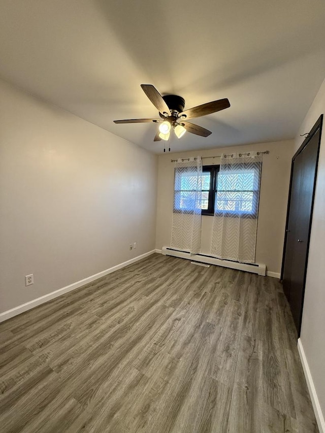 unfurnished bedroom featuring hardwood / wood-style floors, a baseboard radiator, and ceiling fan