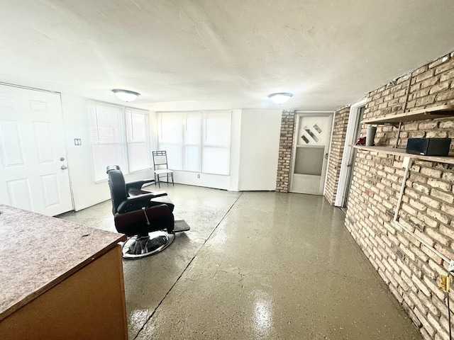 living room featuring a textured ceiling and brick wall