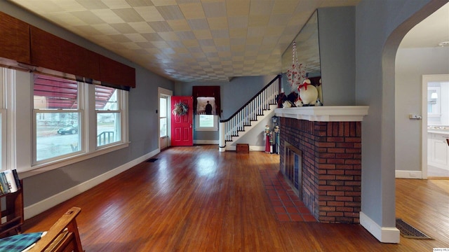 entryway featuring a brick fireplace and dark wood-type flooring