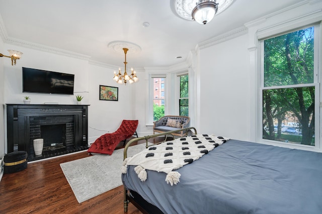 bedroom featuring crown molding, a fireplace, dark wood-type flooring, and an inviting chandelier