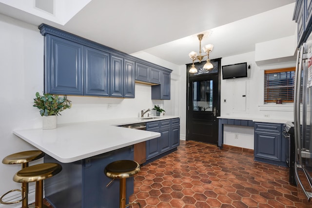 kitchen featuring blue cabinetry, sink, a kitchen breakfast bar, a notable chandelier, and kitchen peninsula