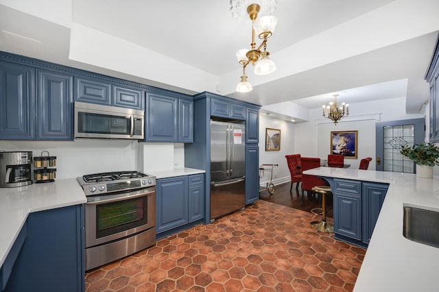 kitchen featuring blue cabinetry, pendant lighting, stainless steel appliances, and a notable chandelier