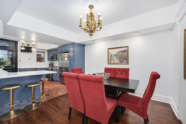 dining space featuring dark hardwood / wood-style flooring, a tray ceiling, and an inviting chandelier