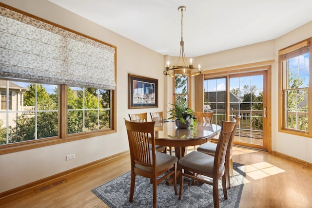 dining space with light hardwood / wood-style flooring and a notable chandelier