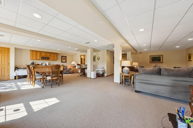 carpeted living room featuring a drop ceiling