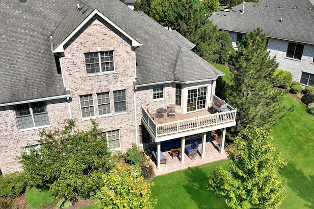 rear view of property with a yard, a deck, and a patio area