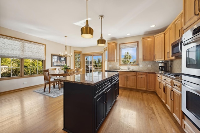 kitchen featuring pendant lighting, dark stone countertops, backsplash, stainless steel appliances, and a kitchen island