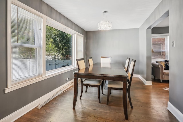 dining space featuring plenty of natural light, dark hardwood / wood-style flooring, and an inviting chandelier