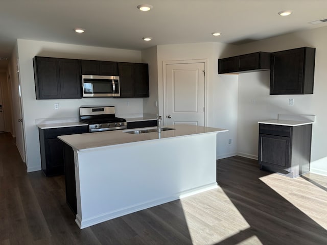 kitchen featuring stainless steel appliances, dark hardwood / wood-style floors, sink, and a center island with sink