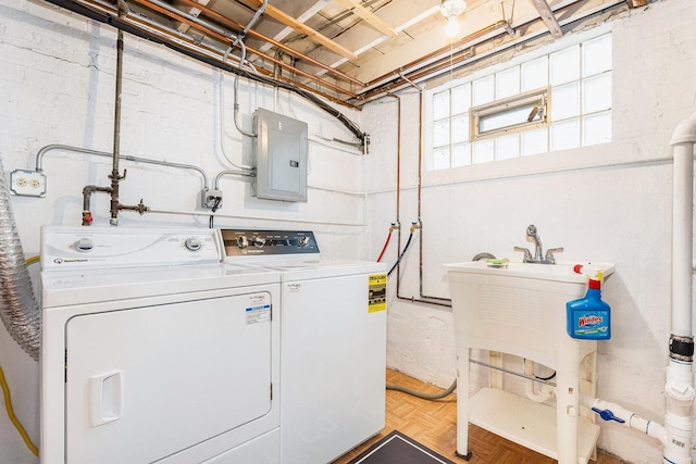 clothes washing area with parquet flooring, electric panel, and washer and clothes dryer