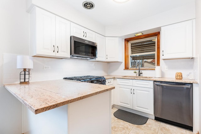 kitchen with white cabinetry, sink, stainless steel appliances, light stone counters, and kitchen peninsula