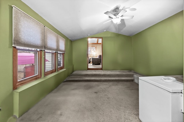 carpeted spare room featuring vaulted ceiling and ceiling fan