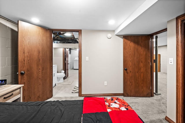 carpeted bedroom featuring ensuite bathroom and washer / dryer