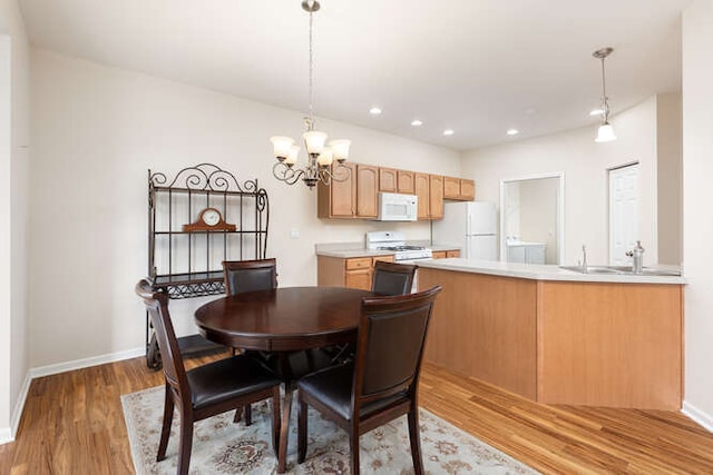 dining space featuring light hardwood / wood-style floors, sink, and an inviting chandelier