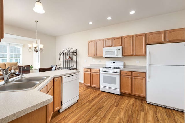 kitchen with pendant lighting, sink, hardwood / wood-style floors, white appliances, and a chandelier