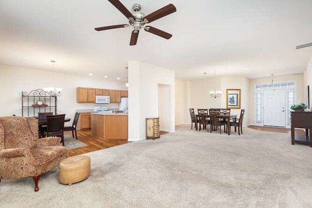 carpeted living room with ceiling fan with notable chandelier