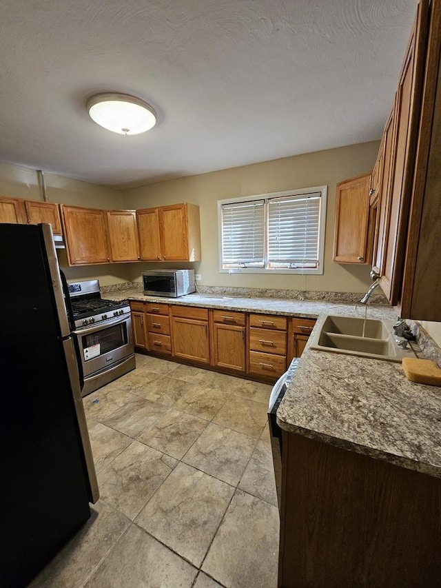 kitchen featuring a textured ceiling, stainless steel appliances, and sink