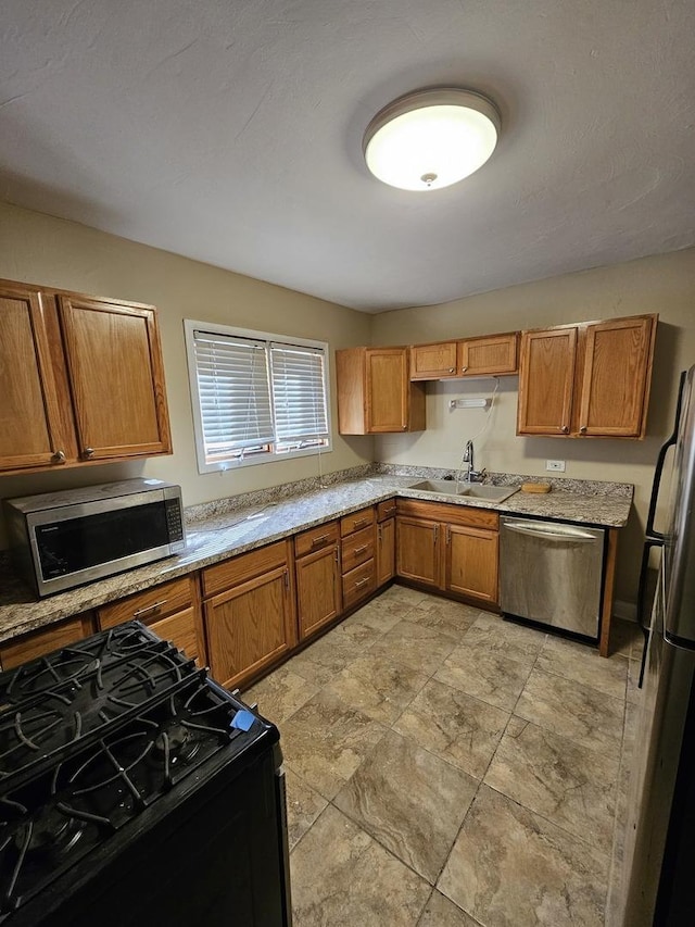 kitchen with light stone counters, sink, and appliances with stainless steel finishes