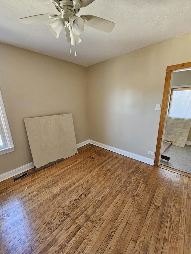 empty room with wood-type flooring, plenty of natural light, and ceiling fan