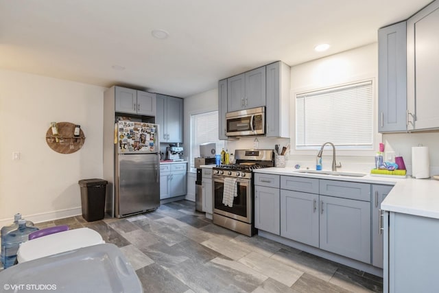 kitchen with appliances with stainless steel finishes, gray cabinets, and sink