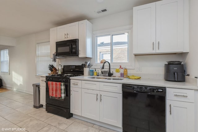 kitchen with light tile patterned floors, sink, white cabinets, and black appliances