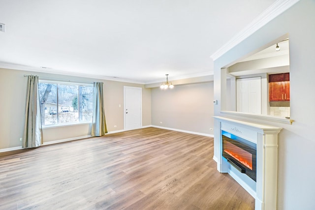 unfurnished living room featuring crown molding, a chandelier, and light wood-type flooring