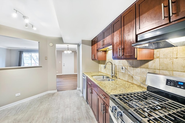 kitchen featuring backsplash, sink, appliances with stainless steel finishes, a notable chandelier, and light hardwood / wood-style floors