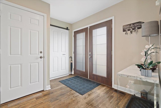 foyer entrance featuring a barn door, french doors, and wood-type flooring