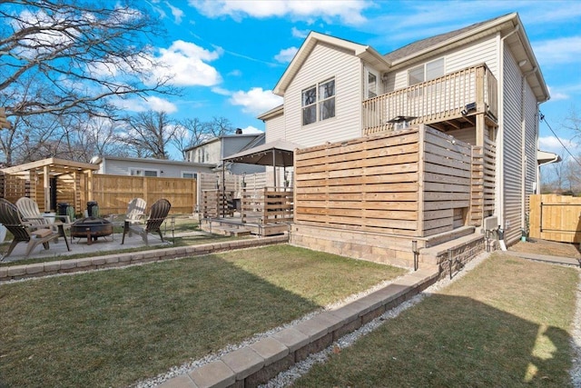 rear view of property featuring a yard, a patio, and a fire pit