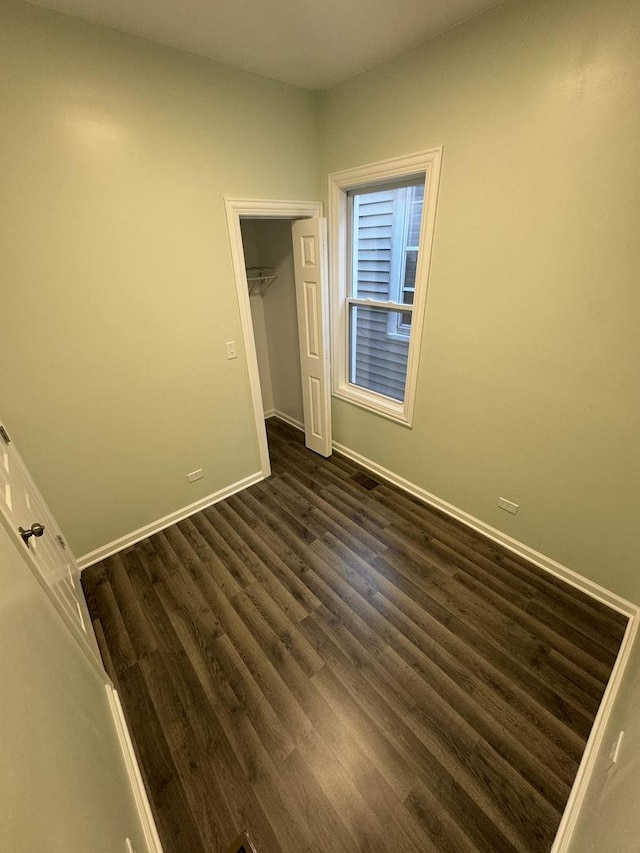 unfurnished bedroom with dark hardwood / wood-style flooring, a spacious closet, and a closet