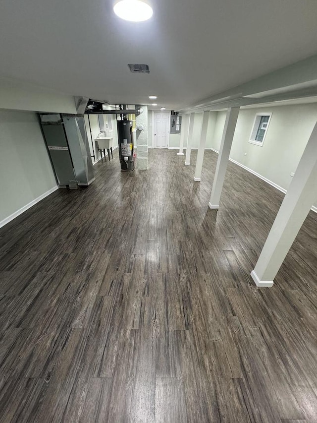 basement with sink, dark wood-type flooring, and water heater