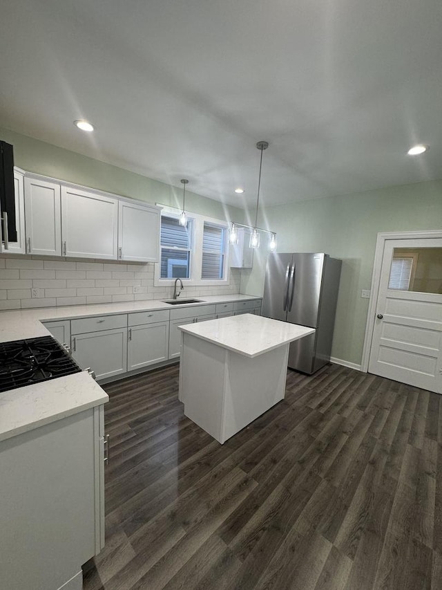 kitchen with stainless steel refrigerator, white cabinetry, a center island, sink, and pendant lighting