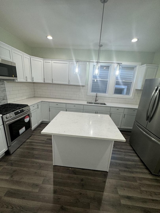 kitchen with sink, a kitchen island, decorative light fixtures, white cabinets, and appliances with stainless steel finishes