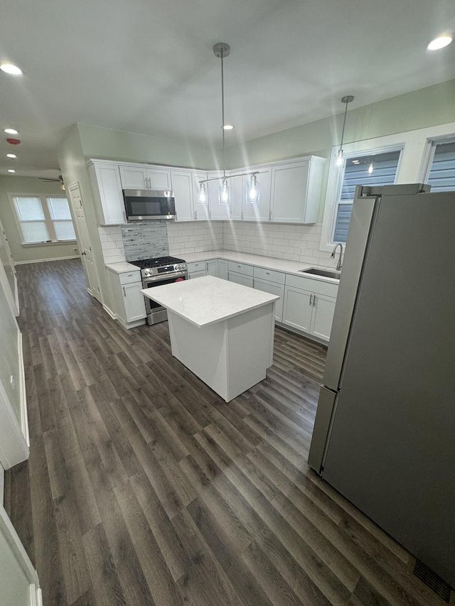 kitchen featuring white cabinetry, hanging light fixtures, stainless steel appliances, and dark hardwood / wood-style floors