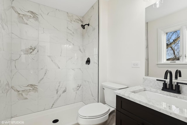 bathroom with vanity, toilet, and a tile shower