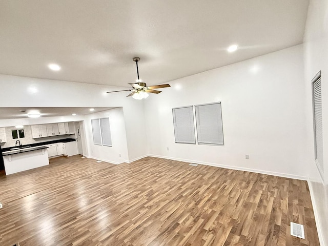 unfurnished living room featuring ceiling fan, light hardwood / wood-style flooring, and sink