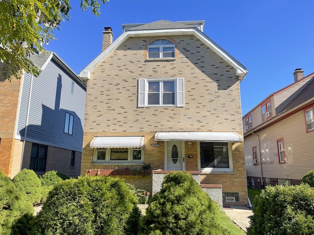 view of front facade with brick siding and a chimney