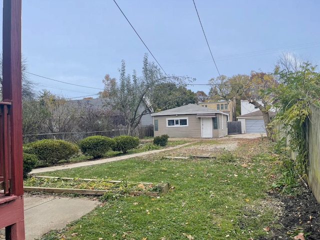 view of yard with an outbuilding, a detached garage, fence, and a garden