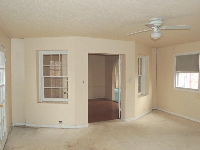 carpeted empty room featuring ceiling fan and a textured ceiling