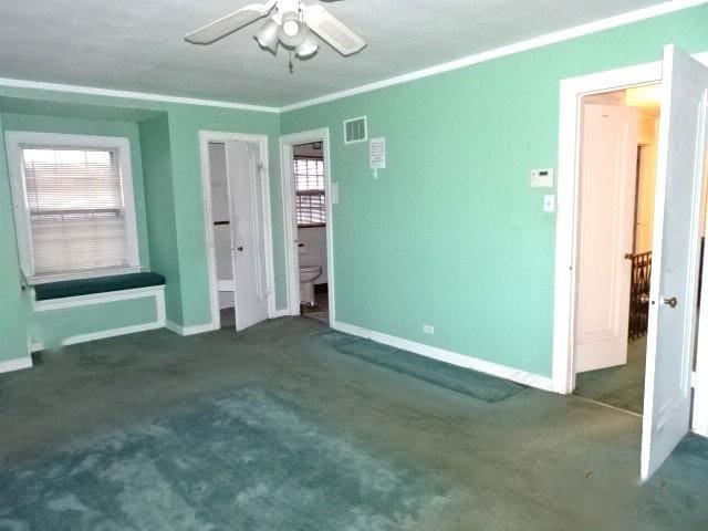 unfurnished bedroom with multiple windows, ceiling fan, ornamental molding, and dark colored carpet