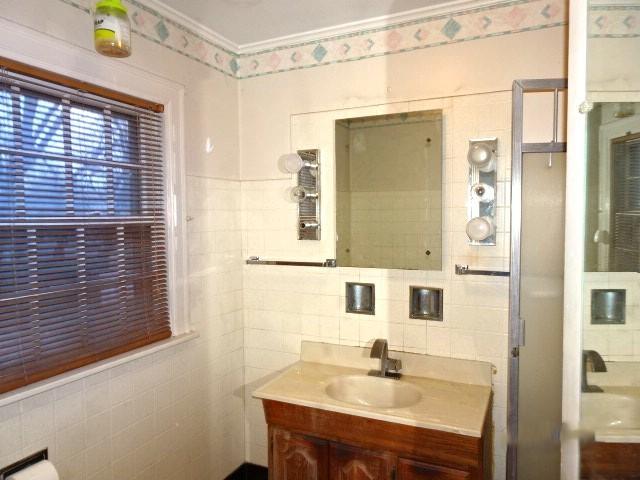 bathroom with vanity, an enclosed shower, tile walls, and ornamental molding