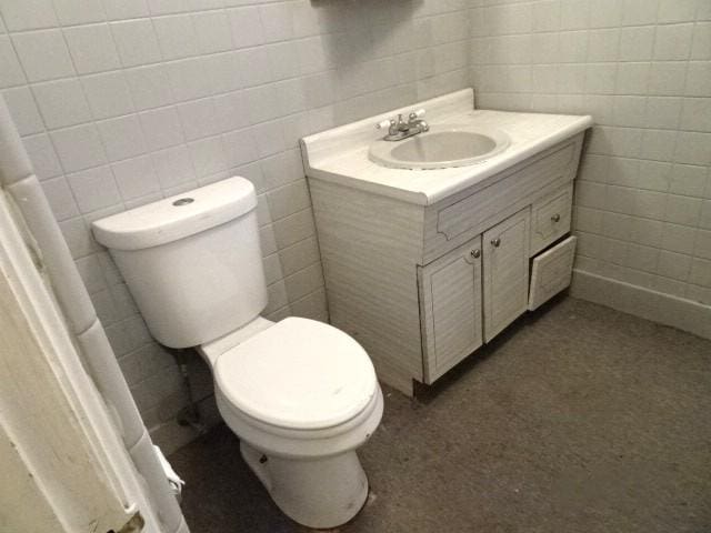 bathroom with vanity, toilet, and tile walls