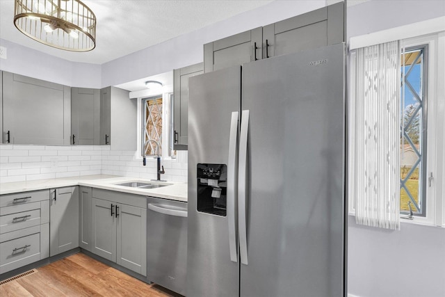 kitchen with gray cabinets, a wealth of natural light, sink, and stainless steel appliances