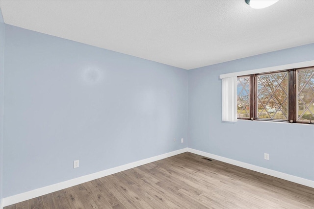 spare room featuring a textured ceiling and light hardwood / wood-style floors