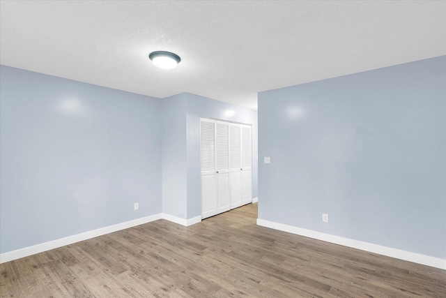 spare room featuring a textured ceiling and light hardwood / wood-style flooring