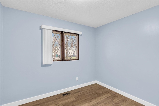 empty room featuring wood-type flooring and a textured ceiling