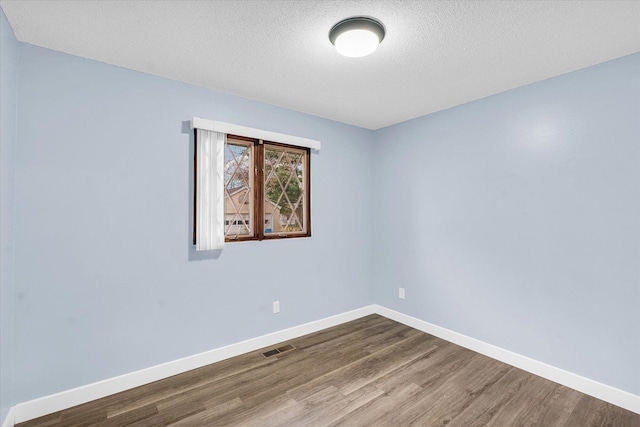 empty room featuring a textured ceiling and hardwood / wood-style flooring