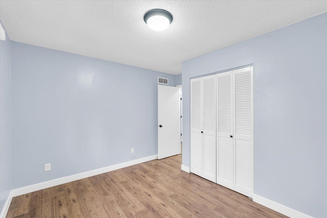 unfurnished bedroom featuring a closet, a textured ceiling, and light wood-type flooring