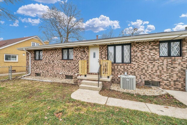 view of front of house with a front lawn and central AC